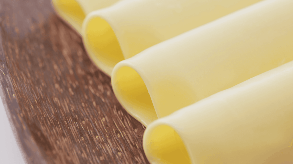 Foto de fatias de queijo mussarela enroladas sobre um prato de madeira