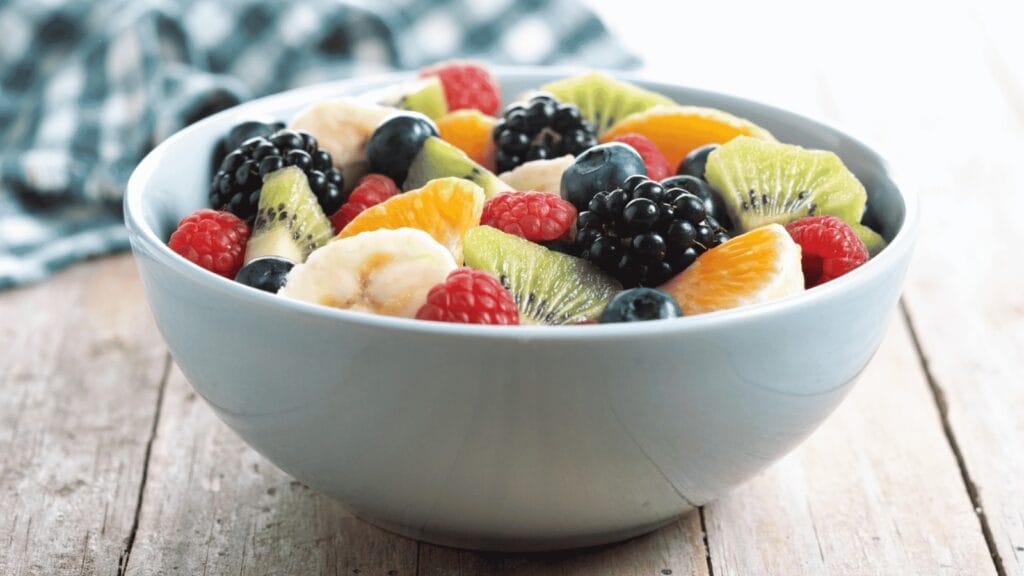 Tigela com frutas variadas como kiwi, morango e banana.