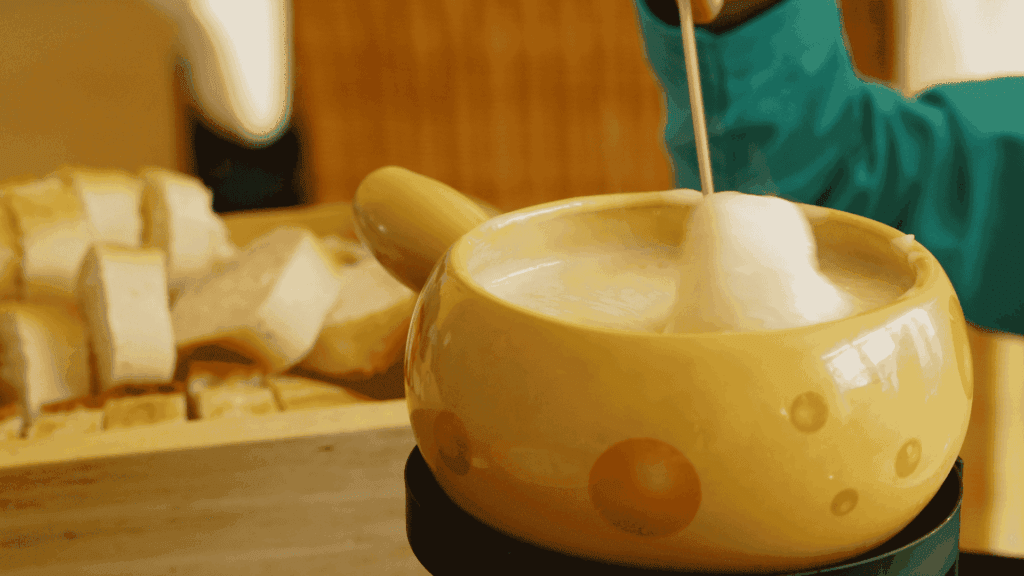Fondue de queijo cremoso acompanhada de cubos de pão.