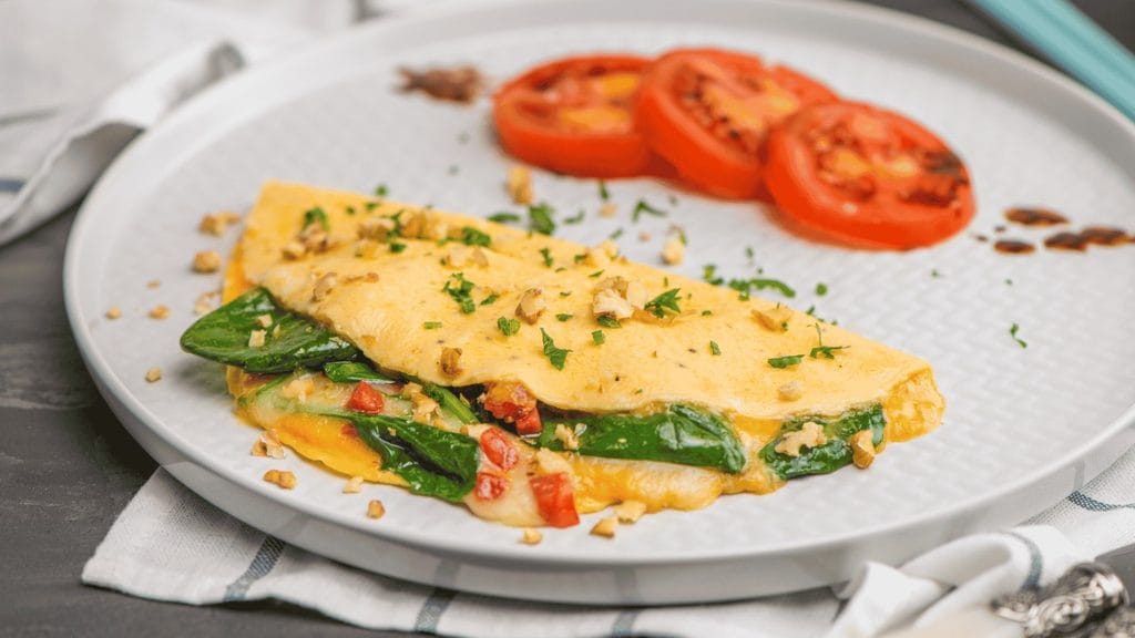 Omelete recheada com queijo servida com tomates grelhados.