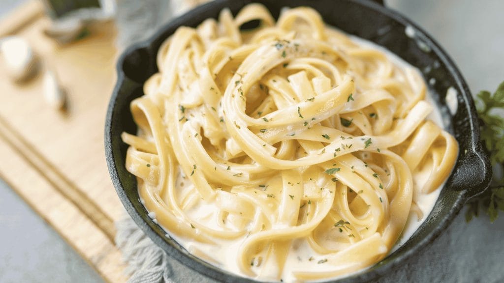 Macarrão cremoso com queijo servido em uma frigideira.